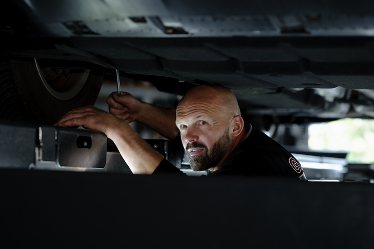 Mitarbeiter von Glaeser Fahrzeugtechnik in Kaltenkirchen bei der Achsvermessung unter einem Fahrzeug